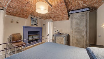 Una stanza con soffitto in mattoni, un letto con materasso blu, una sedia, un tavolino e un armadietto.