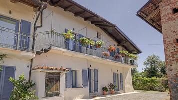 A two-story building with a balcony adorned with potted plants and flowers.