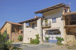 A two-story building with a balcony, a large arched window, and a gravel driveway.