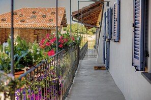 A balcony with a metal railing, potted plants, and flowers.