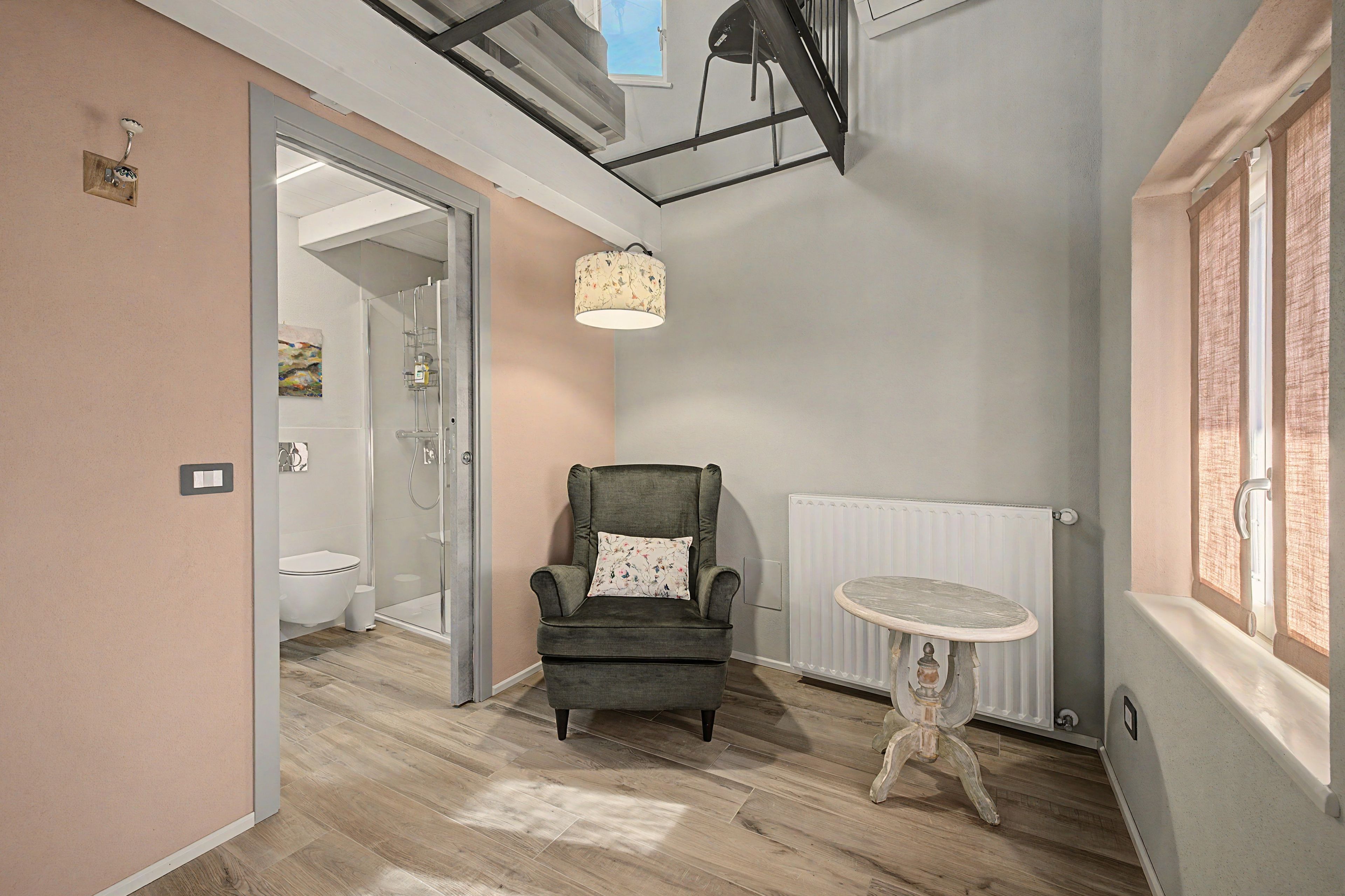 Ein modernes Interieur mit einem grauen Sessel, einem kleinen runden Tisch und einer Heizung.