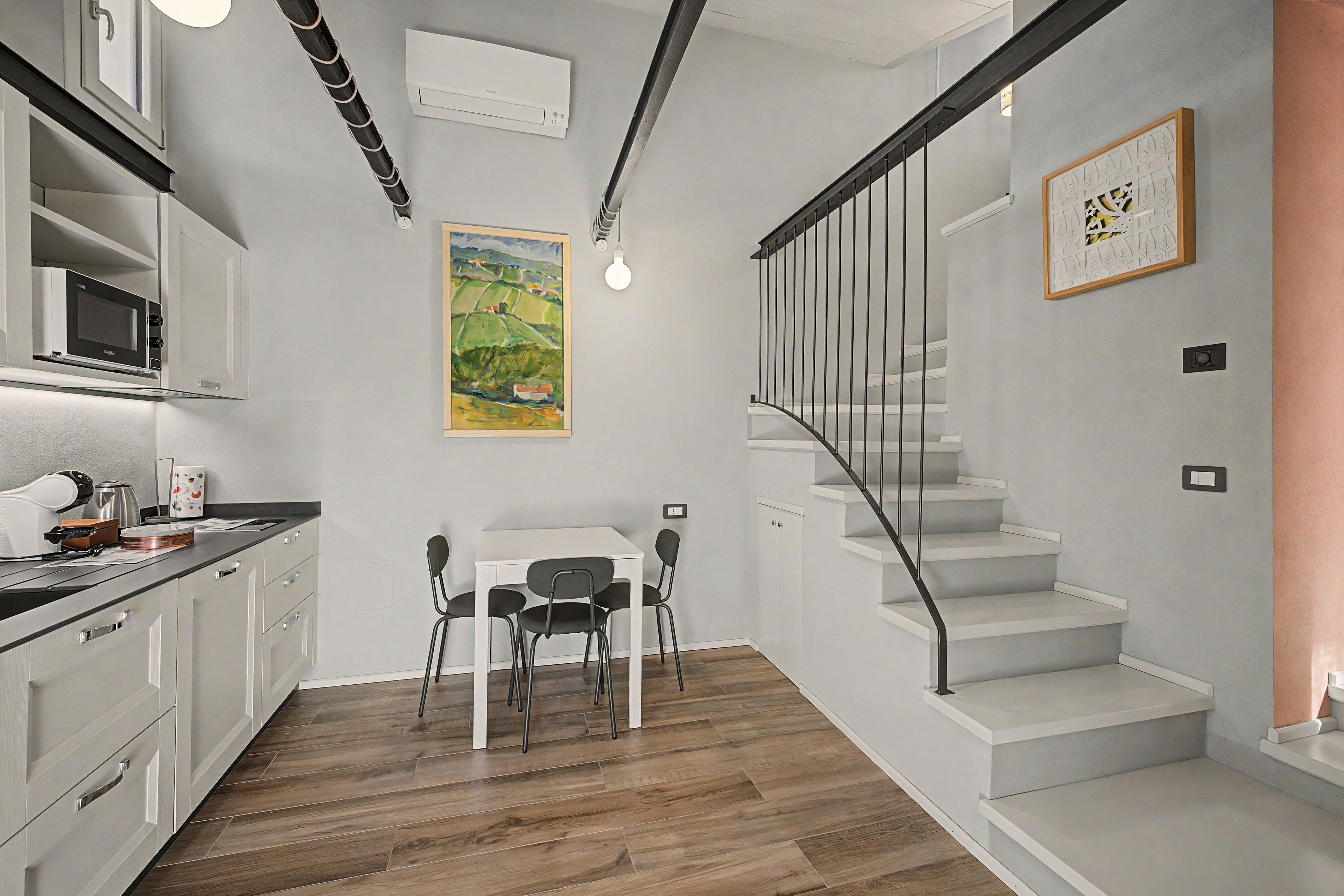 Una cocina moderna con comedor, una escalera y un cuadro en la pared.