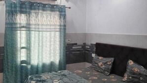 Une chambre à coucher comprenant un lit, un ventilateur de plafond, un appareil de climatisation et un rideau.