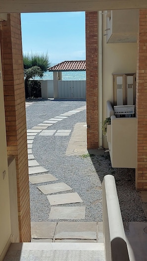 A view of a paved patio area with a patterned stone design, leading to a building with a tiled roof. - APARAMENT 30MT FROM THE BEACH WITH TERRACE AND PARKING (San Vincenzo)