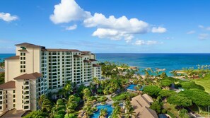 Un resort con un edificio grande, una piscina y vista al océano.