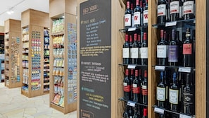 Ein Weinkeller mit Regalen voller verschiedener Weinflaschen und einer Kreidetafel, die Weinsorten und Preise auflistet.