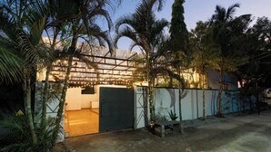 A gated property with a covered entrance, palm trees, and a paved driveway.