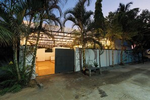 A gated property with a covered entrance, palm trees, and a paved driveway.