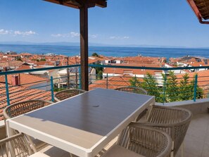 A terrace with a table and chairs, overlooking a coastal town with red-roofed buildings. - Nostos Home by Rentals Pro - Polychrono Halkidiki (Polychrono)