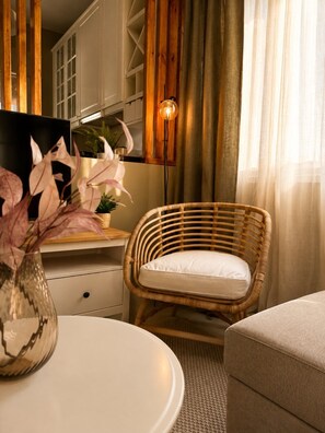 A room with a wicker chair, a white table, a floor lamp, and a painting. - Nostos Home by Rentals Pro - Polychrono Halkidiki (Polychrono)
