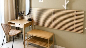 Een kamer met een bureau, stoel, spiegel en een kapstok aan de muur.