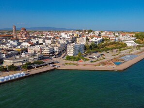 An aerial view of a coastal city with a prominent tower, a marina with boats, and a mix of residential and commercial buildings.