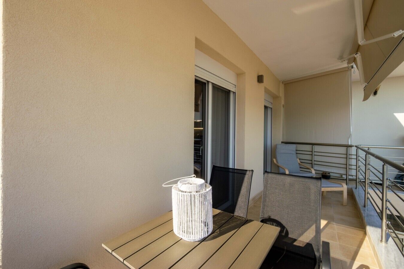 A balcony with a table, chairs, and a white decorative item.
