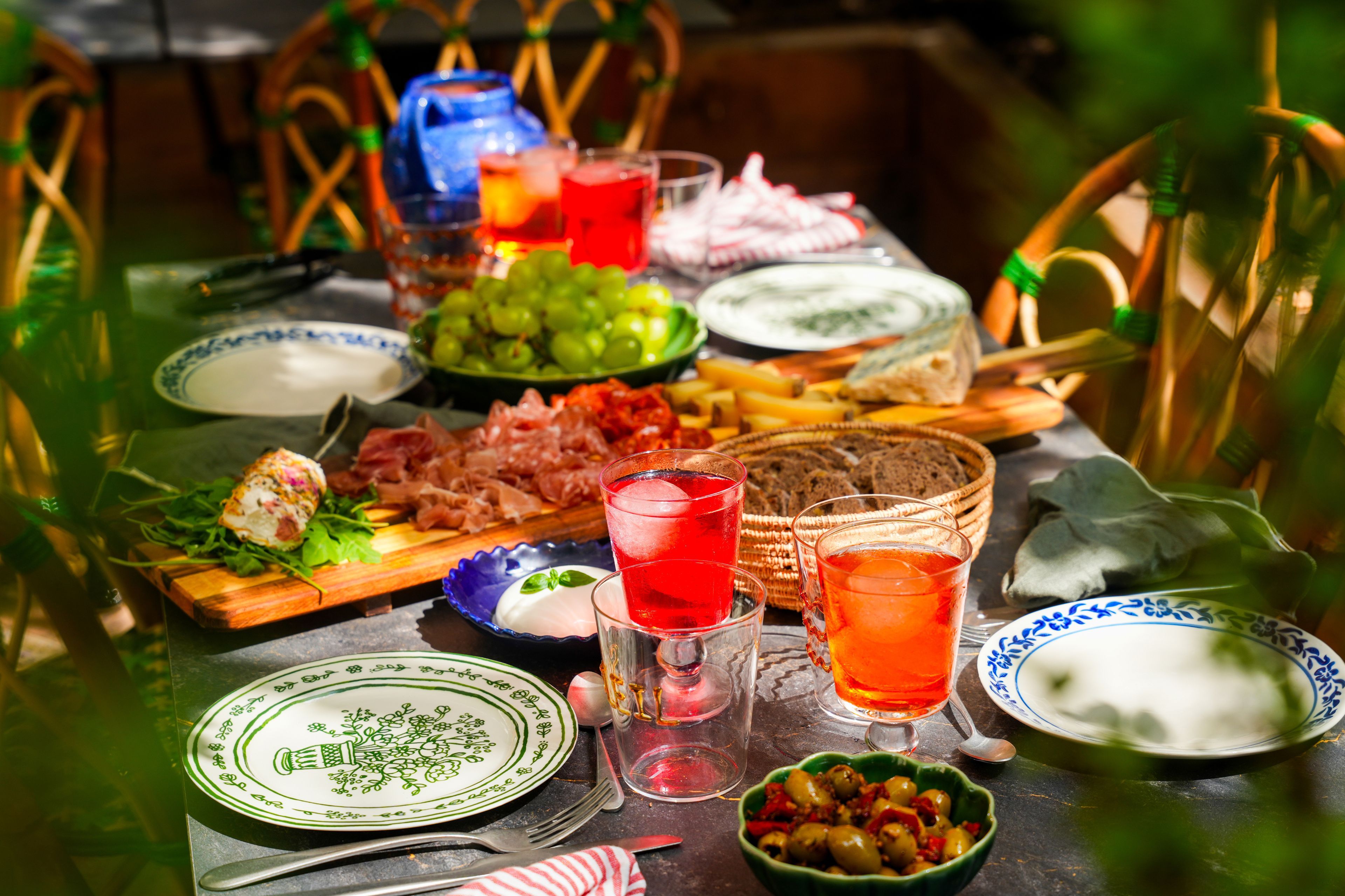 A table set with various dishes, glasses of red beverage, and a bowl of olives.