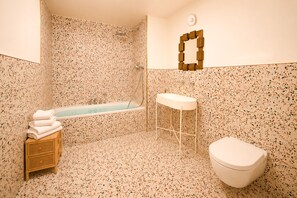 Ein Badezimmer mit einer freistehenden Badewanne, einem weißen Waschbecken und einer Toilette.