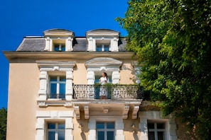 A building with a balcony, a person standing on it, and a tree to the right. - Maison Klara (Montpellier)