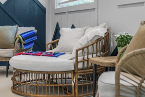 A wicker chair with a white cushion, a blue and red striped towel, and a white pillow. - Indoor Pool! Luxury Design, Game Room, Hot Tub! (Sevierville)