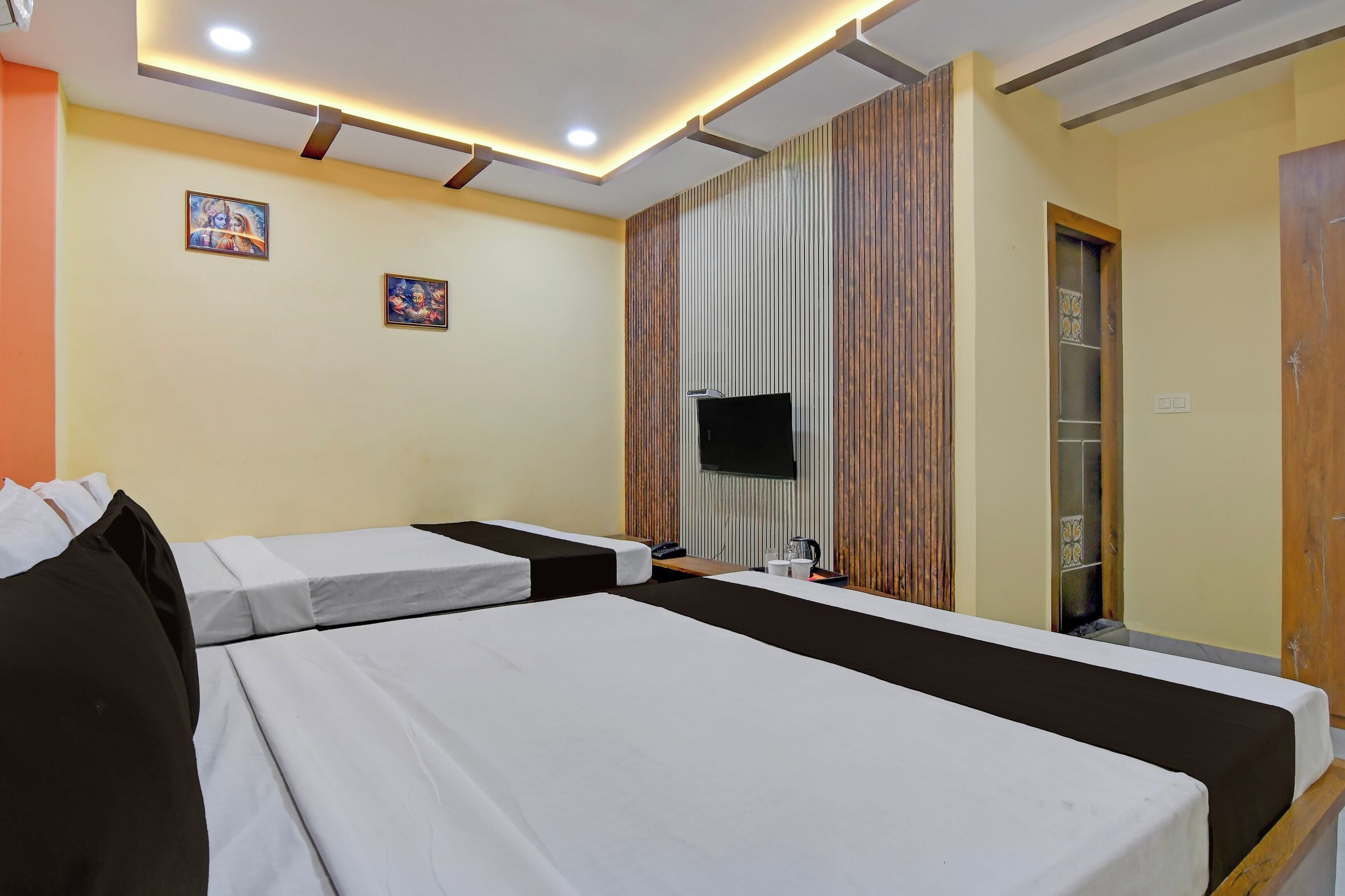 Ein Hotelzimmer mit zwei Betten, einem Fernseher und einer Wandpaneele aus Holz.