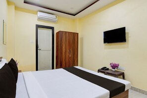A hotel room with a bed, a wardrobe, a television, and a small table with a phone and a vase of flowers. - Collection O Asian Highway Near Agrasen (Jalpaiguri)