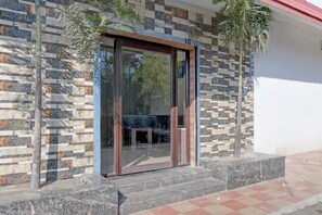 A building entrance with a glass door, stone wall, and steps leading up to a door. - Collection O Asian Highway Near Agrasen (Jalpaiguri)