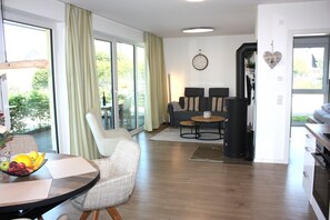 A modern living room with a sofa, a dining table with fruit, and a kitchen area with a stove. - Holiday apartment with infrared sauna, fireplace & terrace in Winterberg (Winterberg)