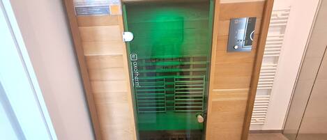 Puerta de ascensor de vidrio con luz verde, un pomo metálico y un panel de control con botones.