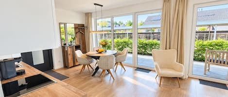 A modern kitchen with a dining area, large windows, and a view of the outside.