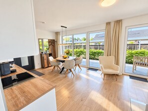A modern kitchen with a dining area, large windows, and a view of the outside. - Holiday apartment with infrared sauna, fireplace & terrace in Winterberg (Winterberg)