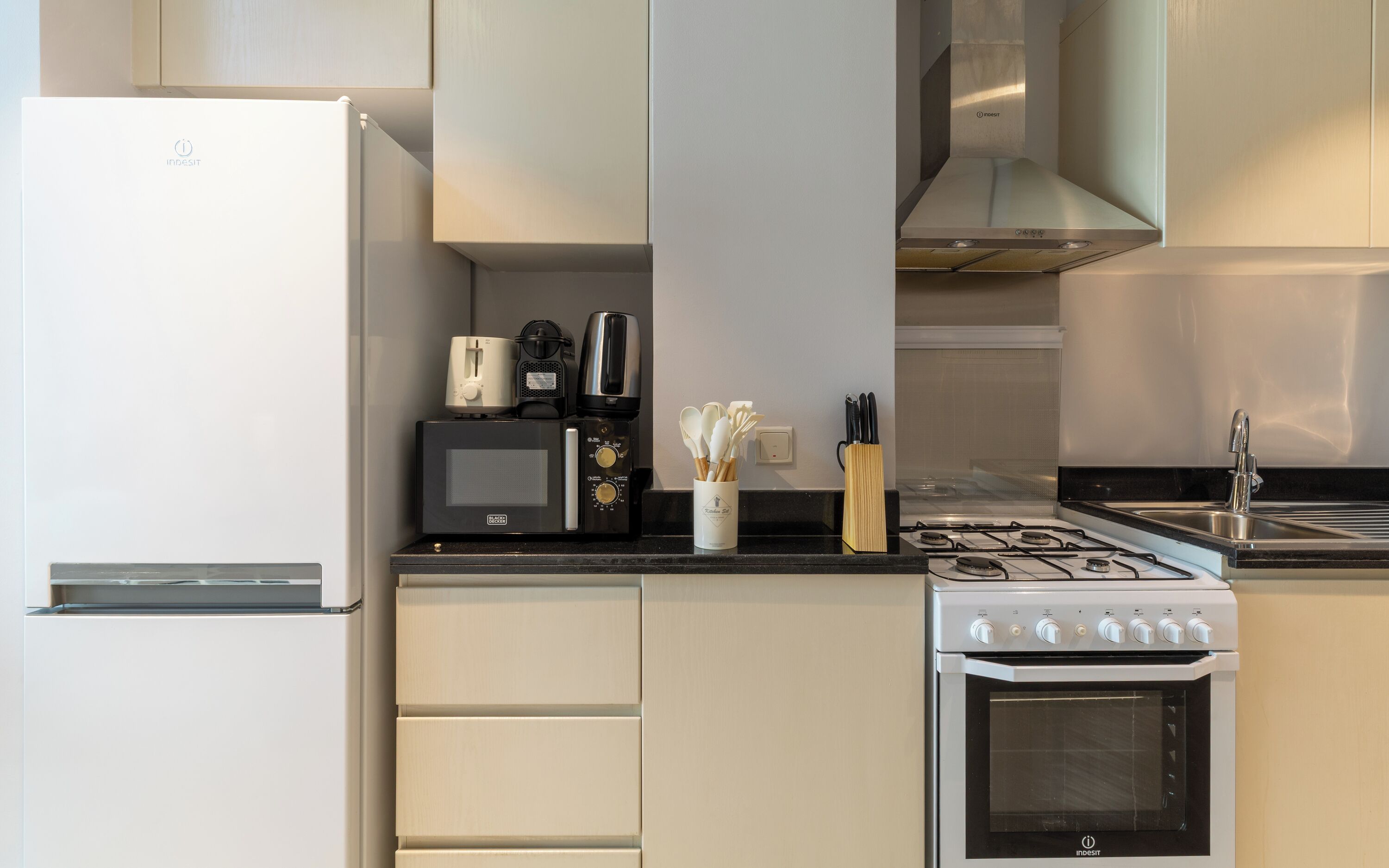 A modern kitchen with a refrigerator, microwave, coffee maker, stove, and oven.