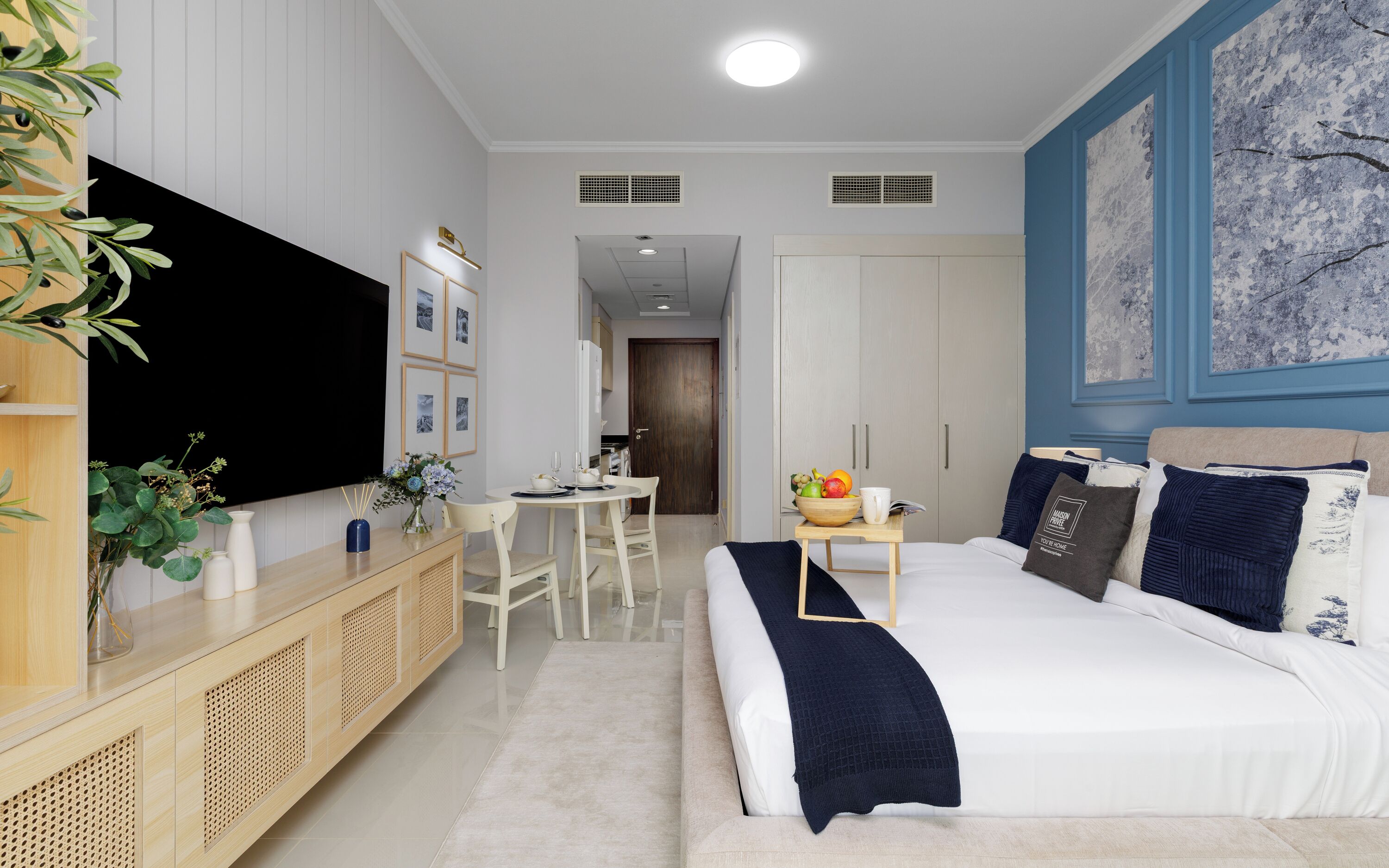 A modern hotel room with a bed, bedside table, and a large flat-screen TV.