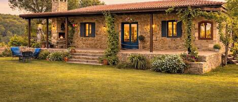 Una casa de piedra con porche cubierto, mobiliario exterior y vistas del paisaje circundante.