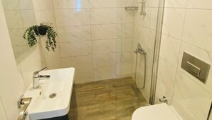 A bathroom with a white sink, toilet, and shower area. - Baraka Bozcaada (Bozcaada)