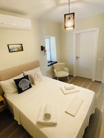 Una habitación de hotel con una cama, una silla, un escritorio y una puerta.