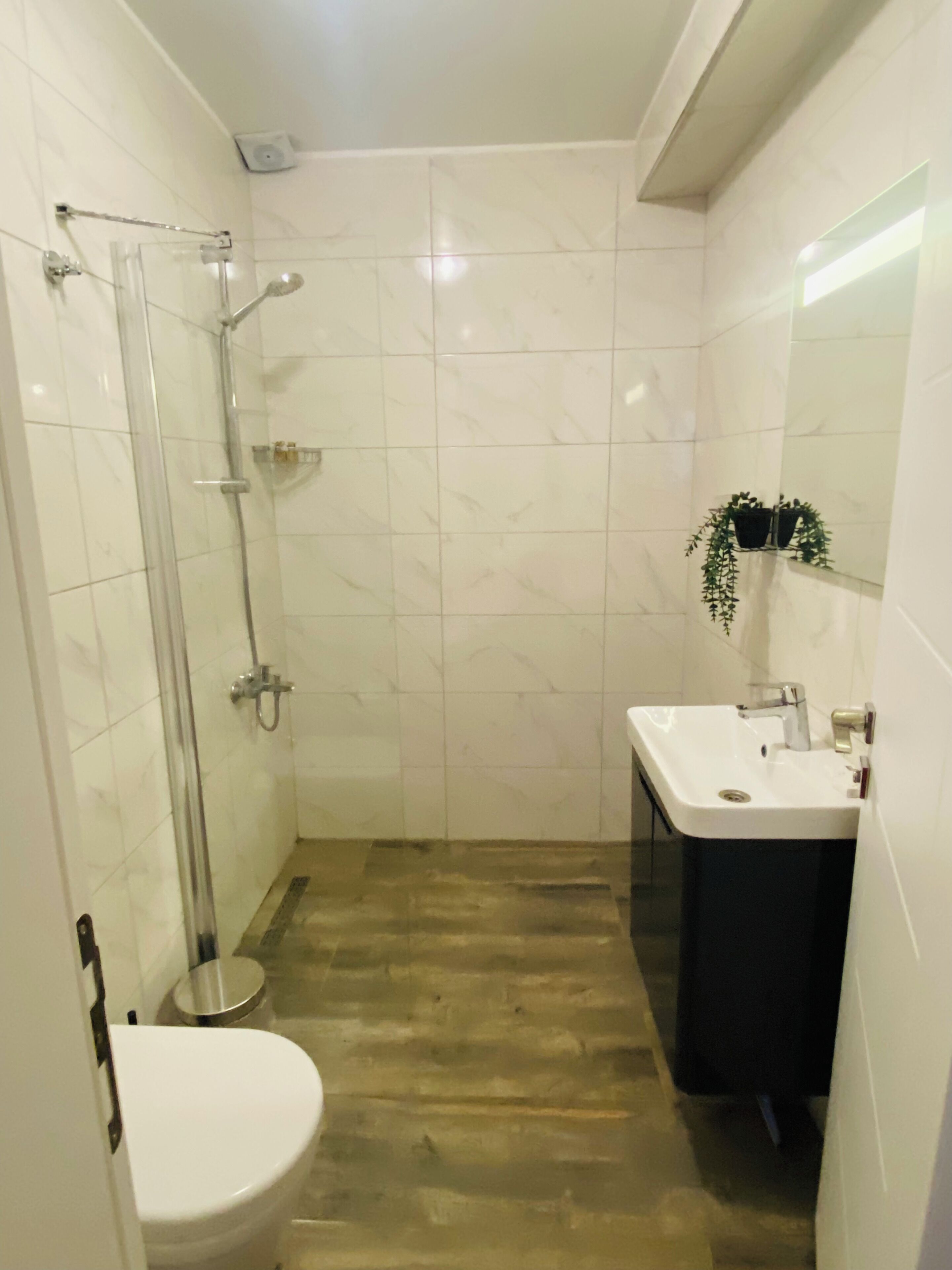 Un baño con cabina de ducha de vidrio, un lavamanos blanco y un inodoro.