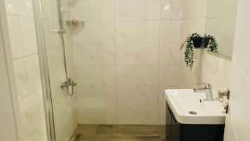 Un baño con cabina de ducha de vidrio, un lavamanos blanco y un inodoro.