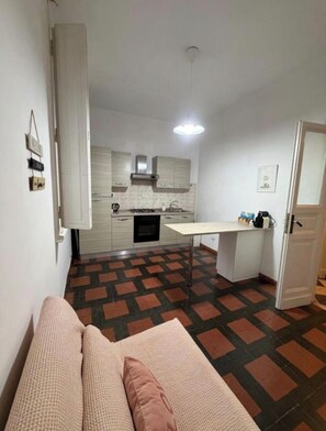 A compact living space with a kitchenette, a sofa, and a patterned floor. - Charming Apartment in San Giovanni—Within Walking Distance of the Colosseum and the Metro (Rome)