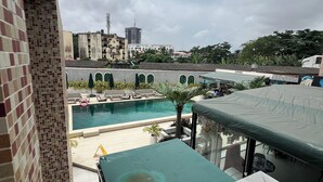 Zona de piscina al terrat amb vistes a edificis propers i un cel amb núvols.