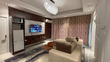Un salon moderne avec un canapé, une table basse, un téléviseur fixé sur un mur en marbre et un rideau à motifs.