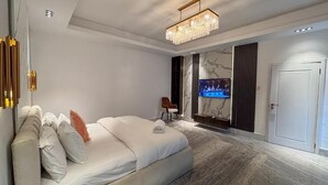 A modern hotel room with a large bed, a television mounted on the wall, and a door on the right. - Mac Residence (Lagos)
