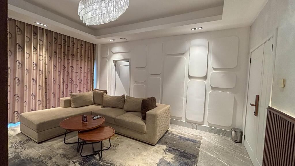 A modern living room with a sectional sofa, a coffee table, and a chandelier.