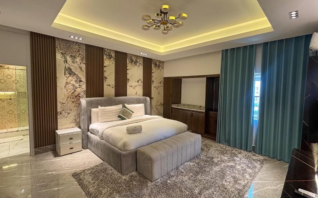 A modern bedroom with a large bed, bedside tables, a dresser, and a mirror.