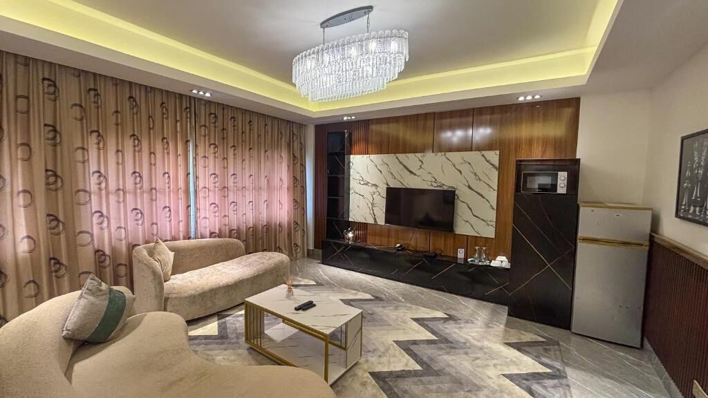 A modern living room with a sofa, coffee table, and a TV mounted on a wall with a marble pattern.
