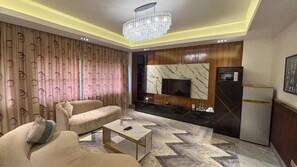Una sala de estar moderna con un sofá, una mesa de centro y un televisor montado en una pared con diseño de mármol.