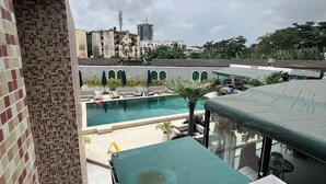 A rooftop pool area with a view of surrounding buildings and a cloudy sky. - Mac Residence (Lagos)