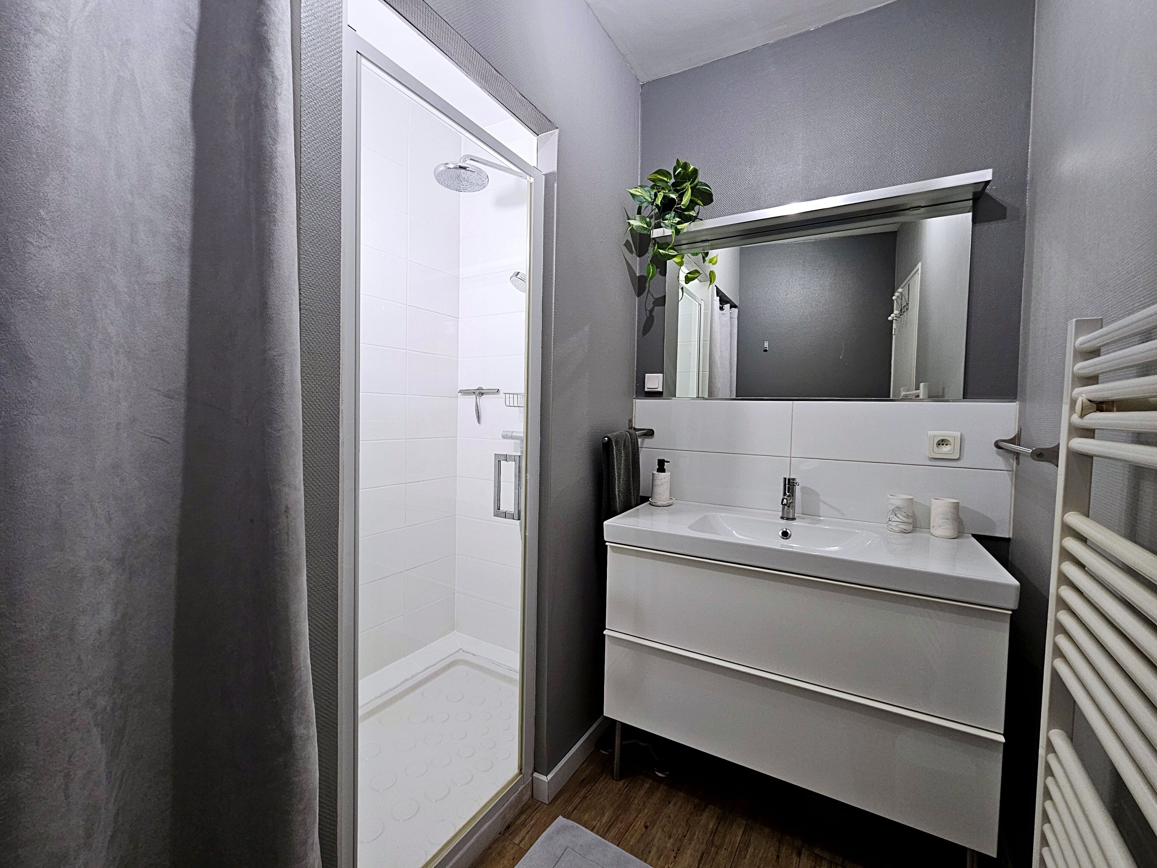 Un baño moderno con ducha, lavamanos, espejo y toallero.