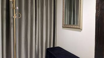 Una habitación con cortina, espejo y una pequeña mesa.