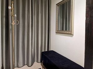 Une pièce avec un rideau, un miroir et une petite table.
