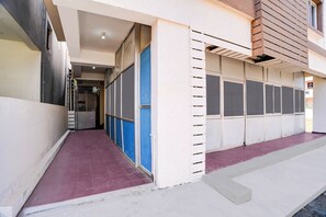 A building with a covered walkway, a gated entrance, and a series of windows.