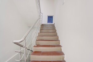 Uma escadaria com corrimãos de metal que leva a uma porta com uma janela acima.