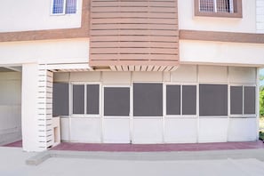 A garage with a white exterior and a brown wooden slatted design above it. - Collection O ChengalpattuRailwayJunction (Chengalpattu)